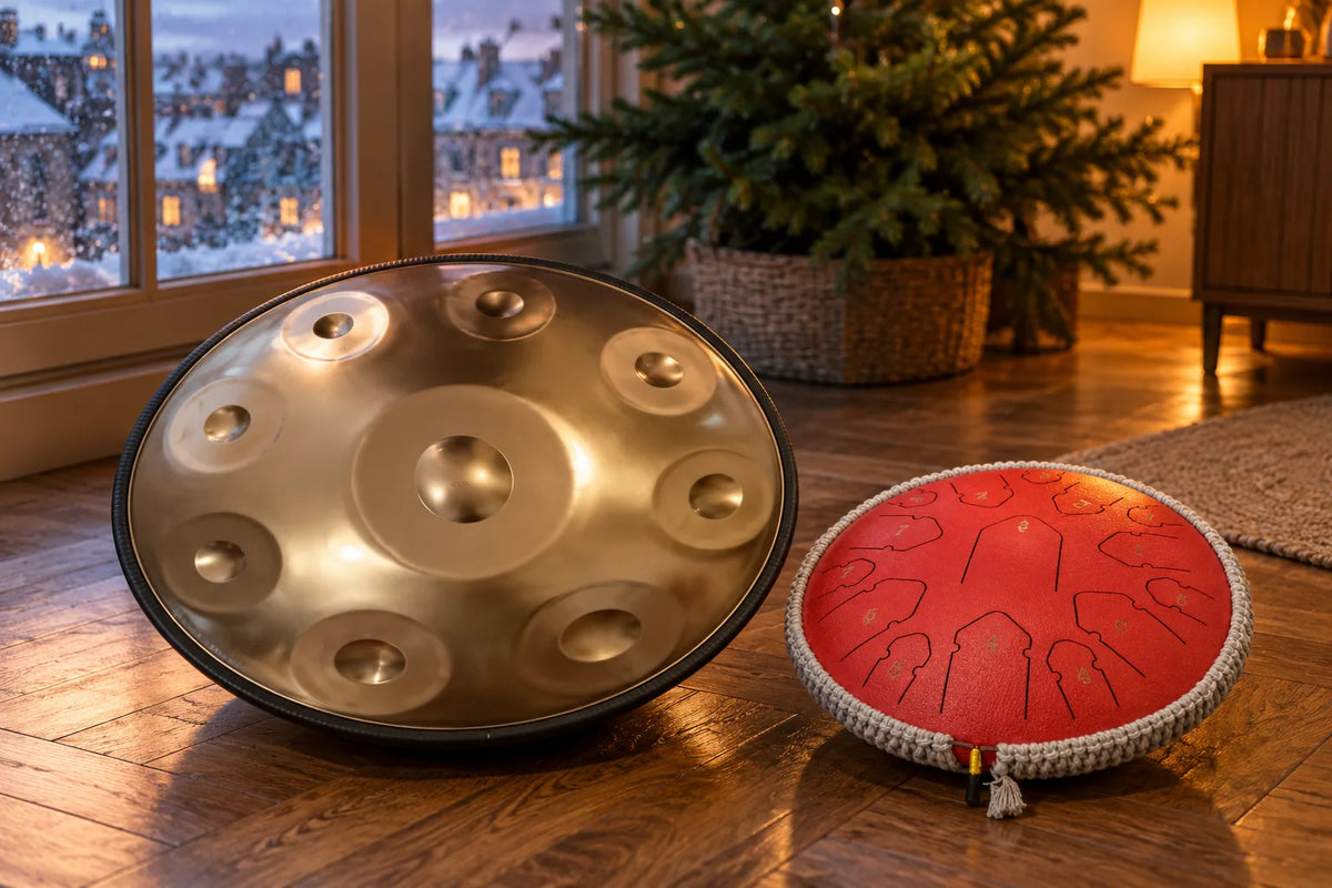 Handpan doré et tongue drum rouge posés près d'une fenêtre enneigée, en décembre