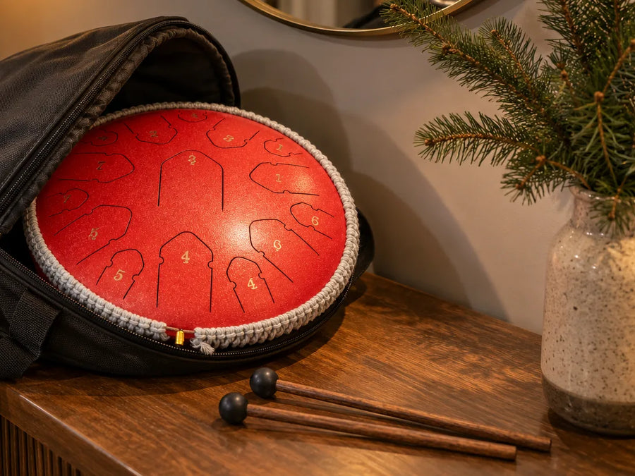 Tongue drum rouge dans sa sacoche ouverte avec ses deux mailloches, prêt à offrir