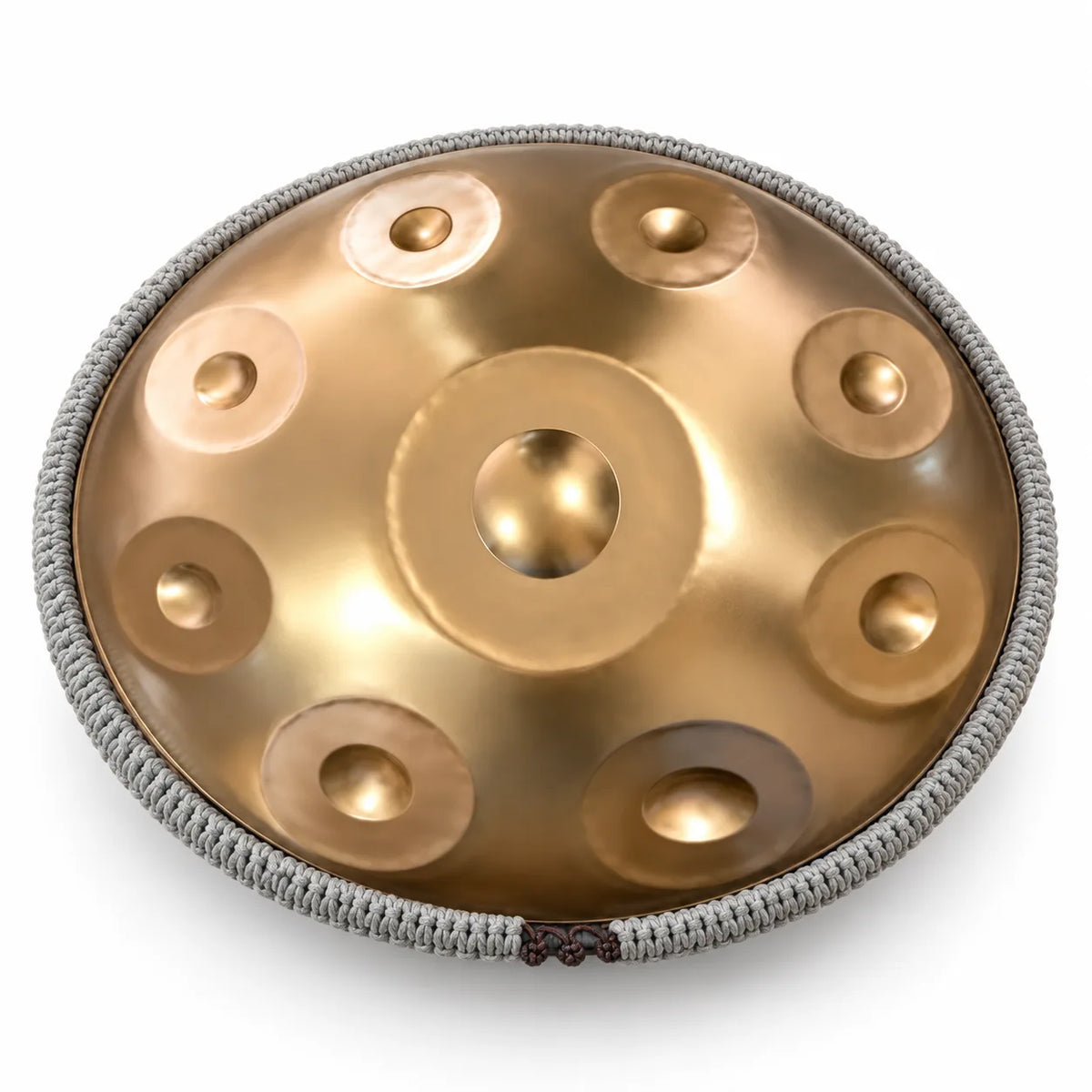 Cordon tressé gris fixé tout autour du bord d'un handpan doré pour le protéger des chocs