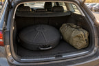 Housse rigide pour handpan calée dans le coffre d'une voiture, à côté d'un sac de voyage