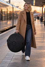 Femme qui porte la housse rigide pour handpan par sa poignée, sur un quai de gare