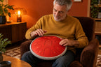 Homme qui joue du bout des doigts sur le tongue drum 15 notes rouge, assis dans un fauteuil